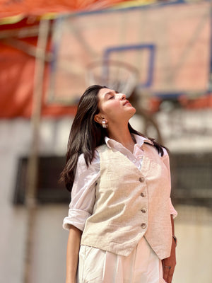 Woman in a light-colored outfit standing in front of a blurred basketball hoop.