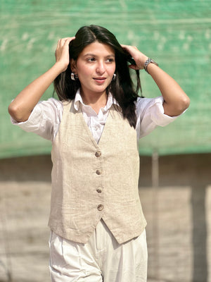 Woman wearing a beige vest over a white shirt with a green background
