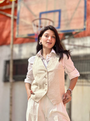 Woman in a light pink vest and white shirt standing in front of a basketball hoop.