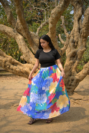 Person wearing a colorful skirt standing in front of a tree with a natural trendybuzzbackground