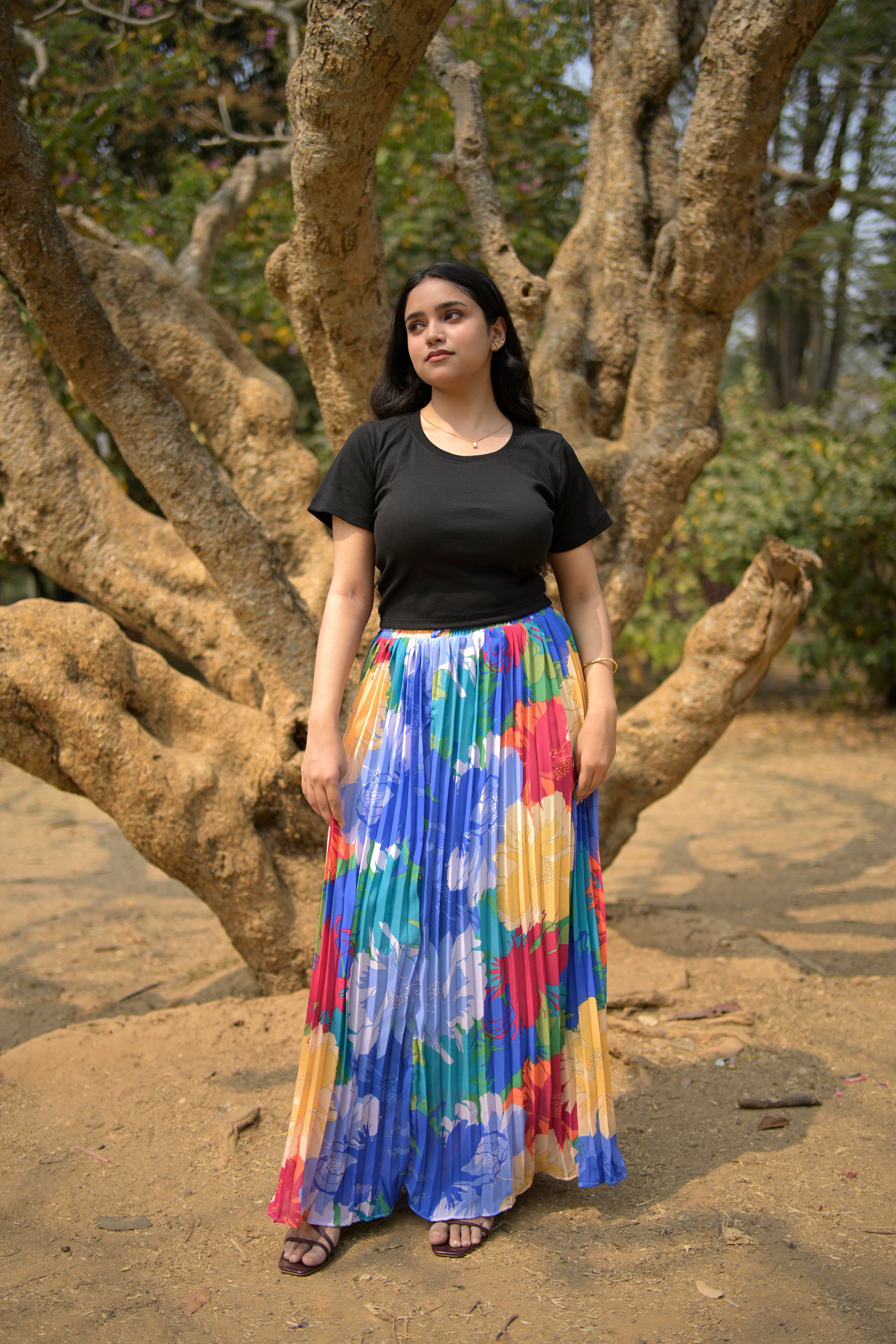 Woman holding a colorful skirt under a tree trendybuzz