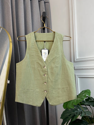Green vest on a hanger against a gray curtain background