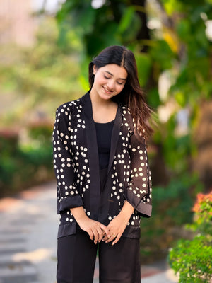 Woman wearing a black blazer with white polka dots in an outdoor setting
