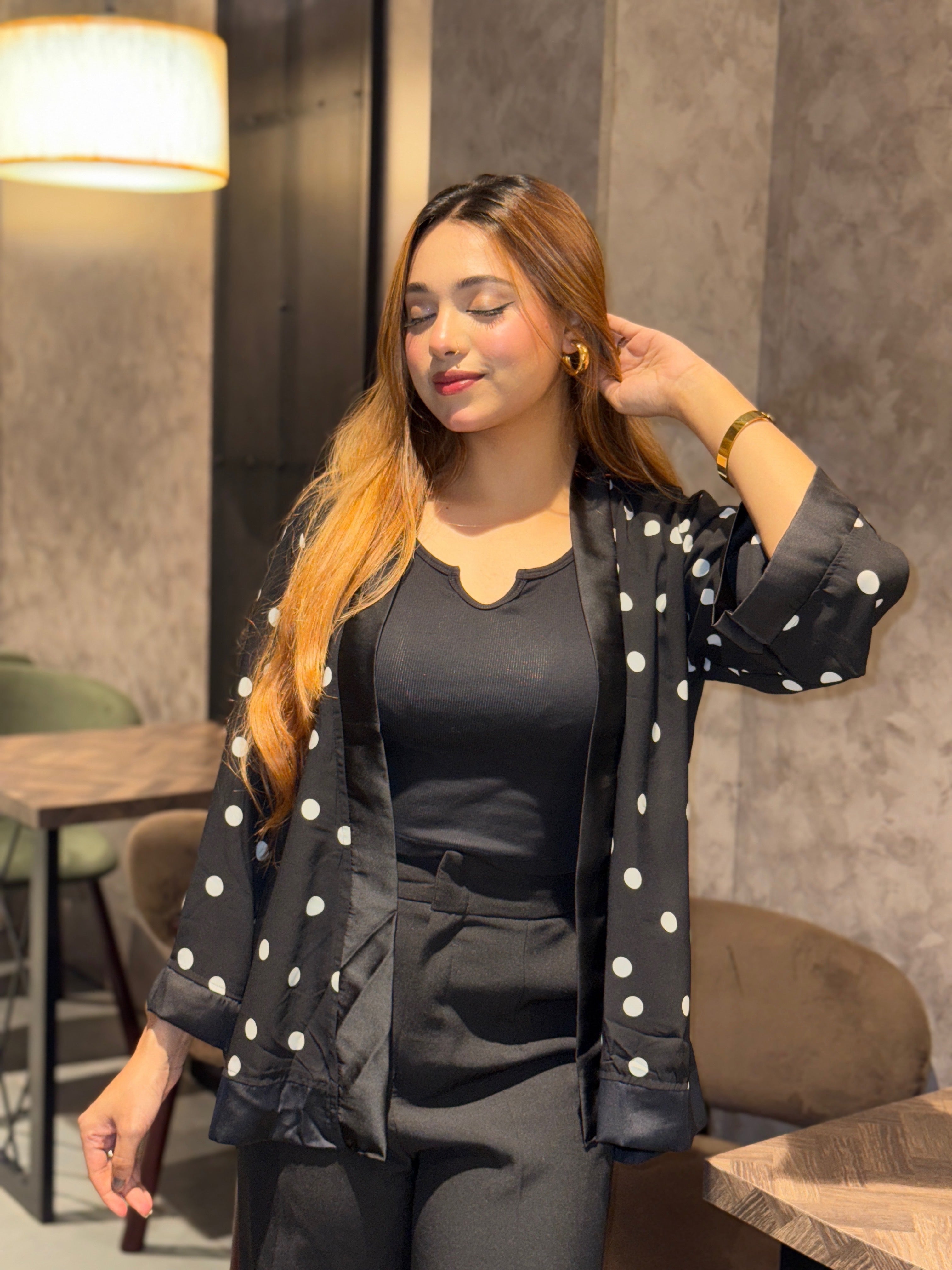 Woman wearing a black Kimono outfit with white polka dots in an indoor setting