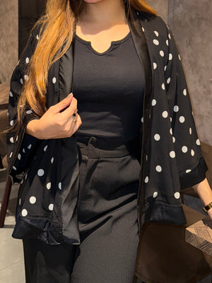Person wearing a black outfit with a white polka dot Kimono indoors.
