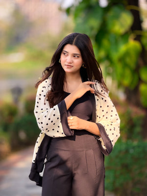 Woman wearing a polka dot shirt over a dark outfit with a blurred green background