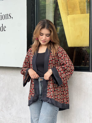 Woman wearing a patterned short kimonos in front of a store window
