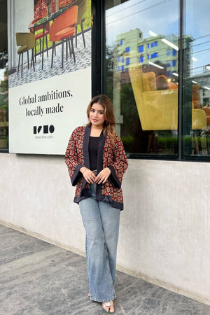 Woman wearing short kimonos standing in front of a building with a large sign and chairs displayed.