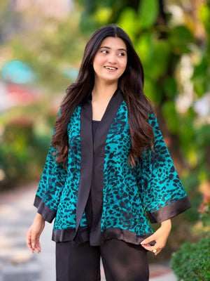 Woman wearing a teal leopard print kimono with a blurred green outdoor background