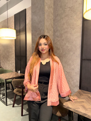 Woman sitting at a table in a modern restaurant setting wearing our Misty polka dot Kimono over a black top