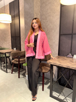 Woman in a pink polka dot kimono sitting at a table in a modern cafe.