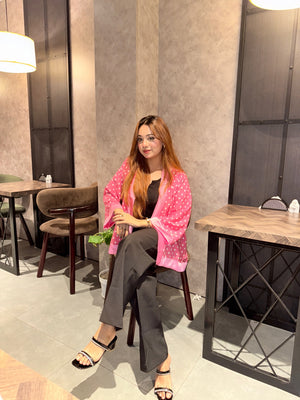 Woman sitting at a table in a modern cafe setting wearing our pink polka dot kimono