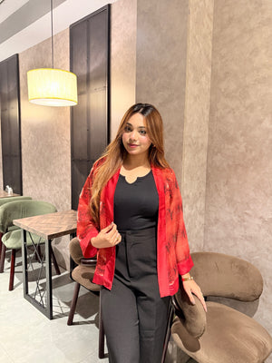 Woman in a red snake print kimono and black outfit sitting in a modern cafe.