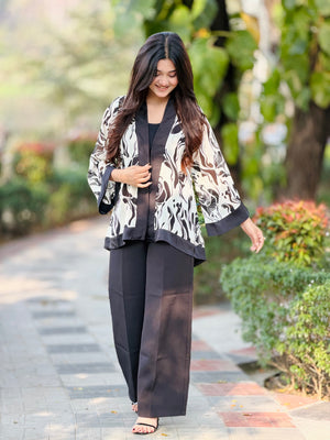 Woman in a patterned jacket and black pants walking outdoors on a path with greenery.