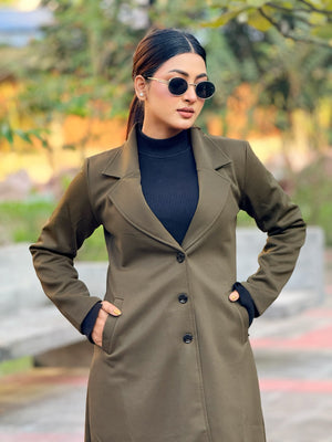 Woman wearing a long brown coat and sunglasses outdoors with blurred background