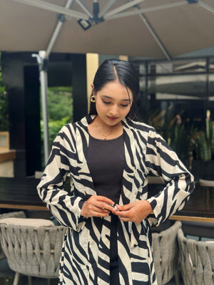 Woman wearing a black and white patterned long shrug in an outdoor setting