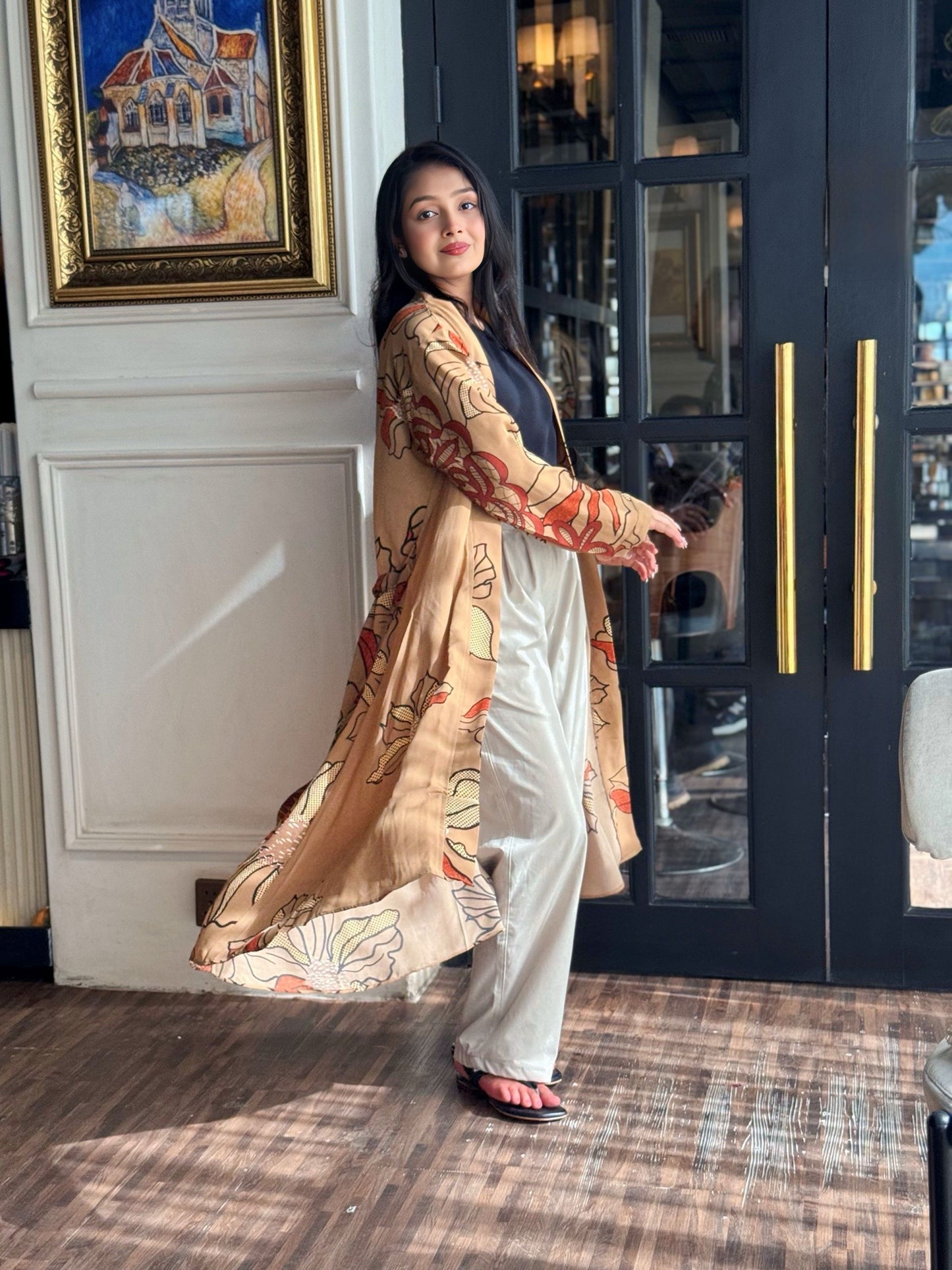 Woman in a traditional outfit standing in a room with a painting and door in the background