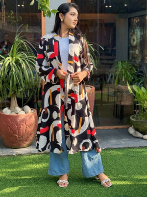Woman wearing a colorful patterned long shrug standing outdoors with plants in the background