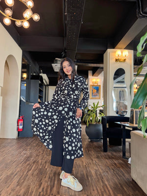 Woman in a polka dot dress posing in an indoor setting with modern decor.