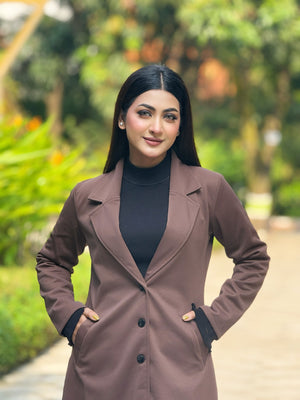 Woman wearing a brown coat with a blurred green outdoor background