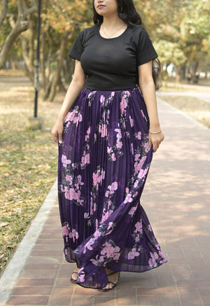 Woman wearing a black top and purple floral skirt on a path with trees in the background TrendyBuzz