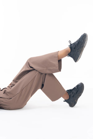 Person wearing brown pants and black shoes on a white background