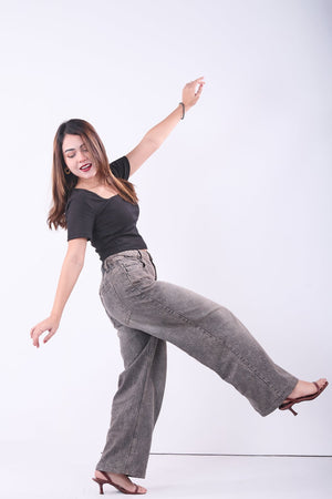Woman posing in black top and gray pants on a white background