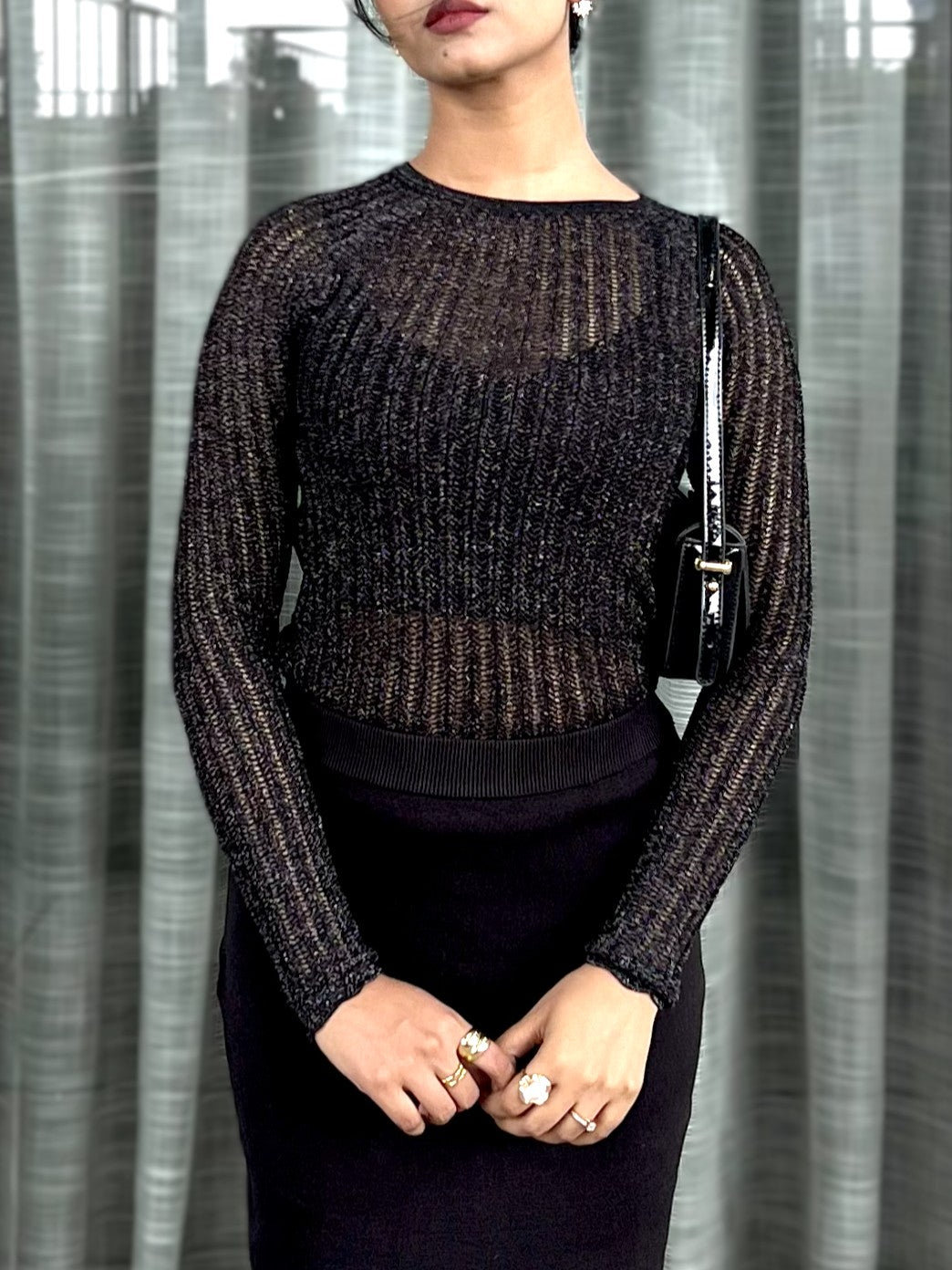 Woman wearing a black textured mesh top which is glittery for party use. trendy buzz