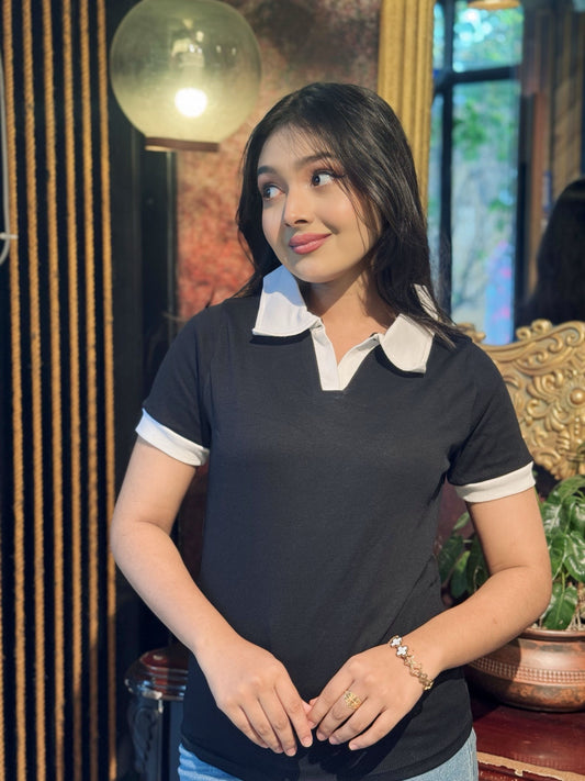 Woman wearing a black and white polo shirt in an indoor setting