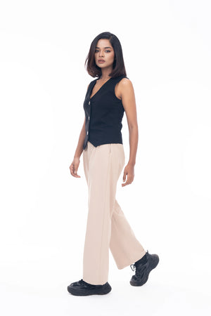 Woman wearing a black sleeveless top and beige pants on a white background