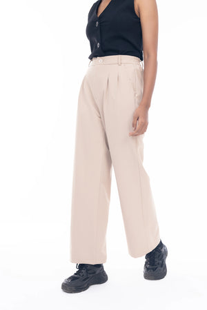 Person wearing a black sleeveless top and beige pants on a white background