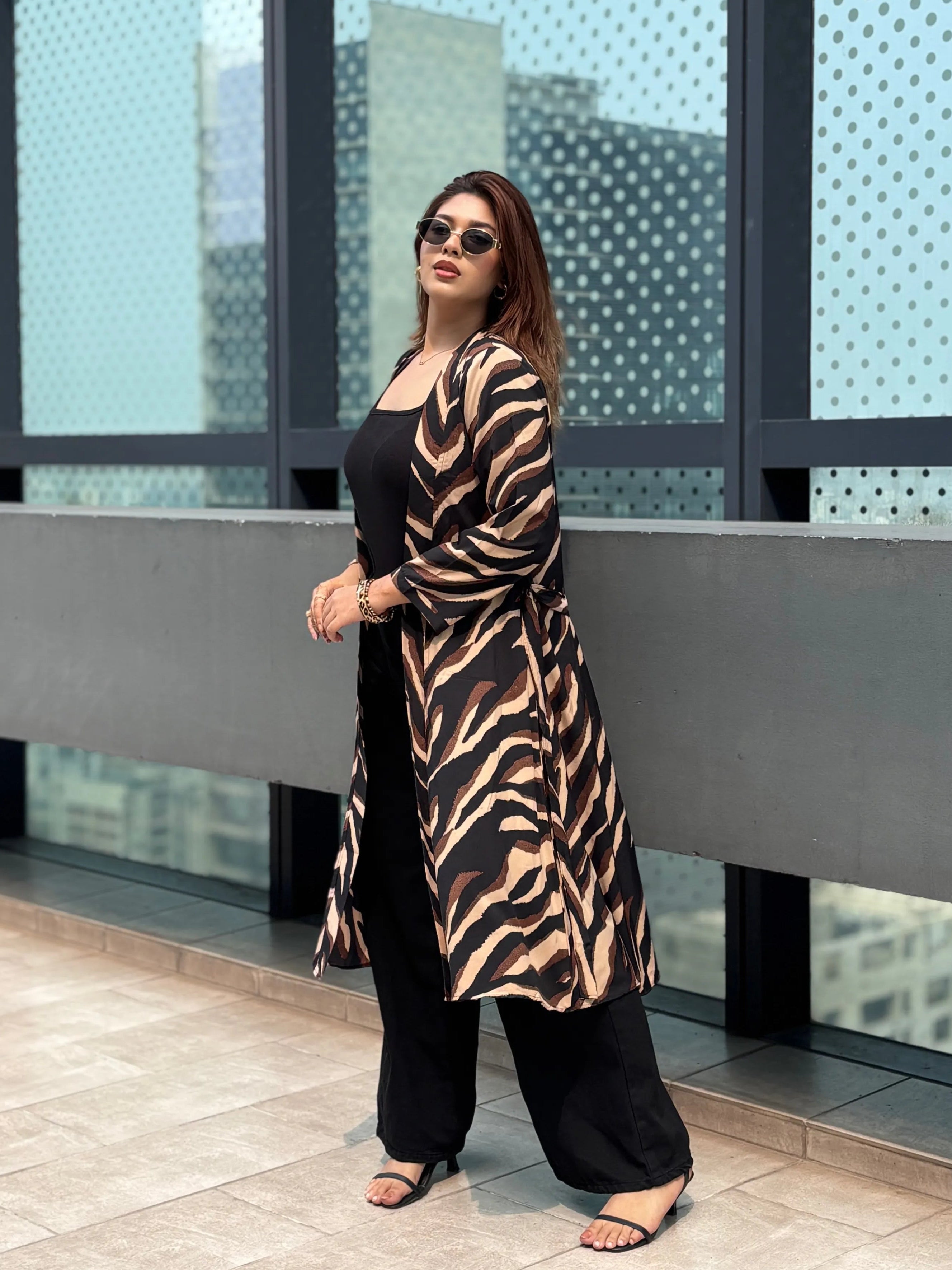 Woman wearing a zebra print Shrug standing on a balcony with a cityscape background