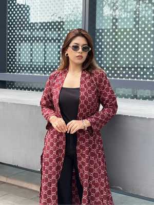 Woman wearing a red patterned Shrug and sunglasses standing in front of a modern building.