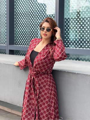 Woman in a red patterned Shrug standing against a modern building facade.