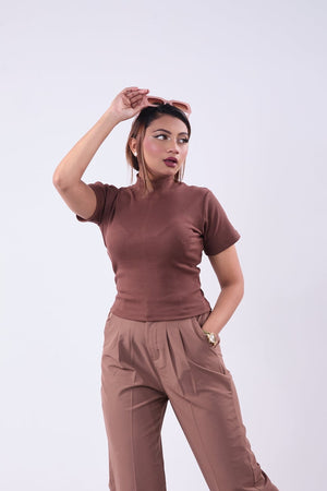 Woman wearing a brown outfit posing against a white background