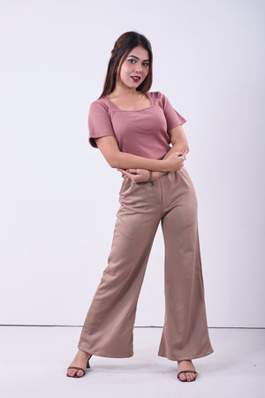 Woman wearing a pink top and brown pants on a white background
