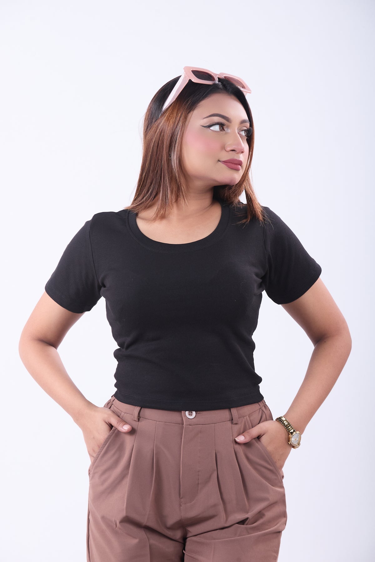 Woman wearing a black t-shirt and brown pants on a white background