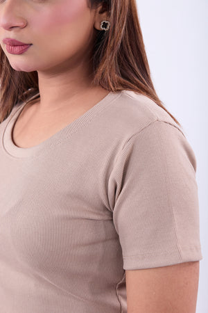 Close-up of a person wearing a beige ribbed sweater on a white background
