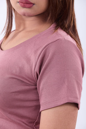 Close-up of a person wearing a pink ribbed sweater on a white background