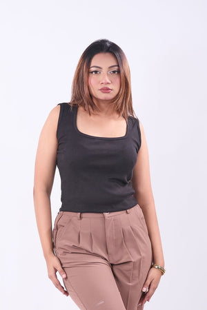 Woman wearing a black sleeveless top and brown flared pants on a white background