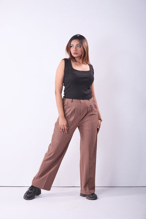 Woman wearing a black sleeveless top and brown pants on a white background