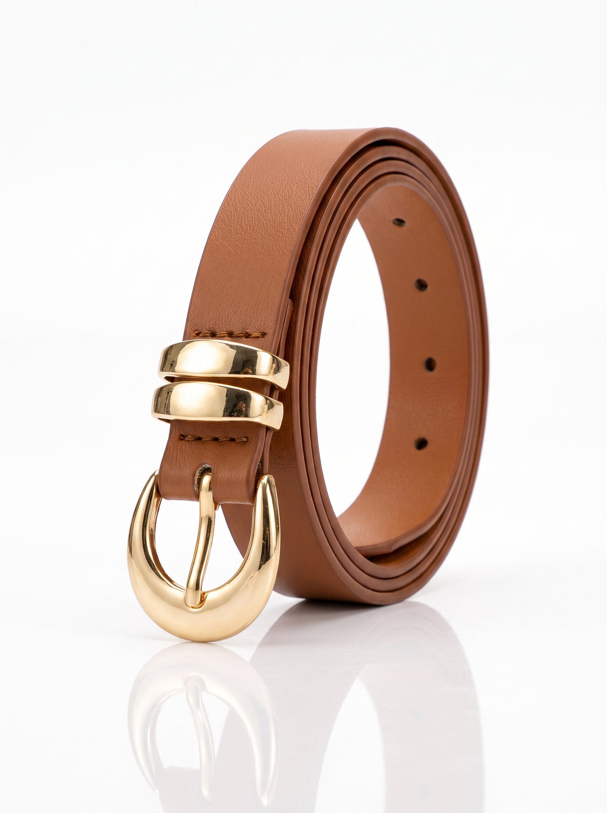 A brown leather belt with a polished gold-tone buckle, coiled on a reflective white surface.