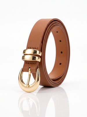 A brown leather belt with a polished gold-tone buckle, coiled on a reflective white surface.