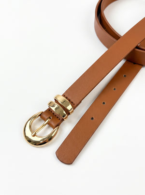 A brown leather belt with a polished gold-tone buckle, shown coiled on a clean white background.