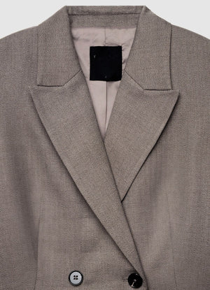 Close-up of a Calliope blazer in a textured taupe-gray fabric, showing the collar, lapels, and buttons.