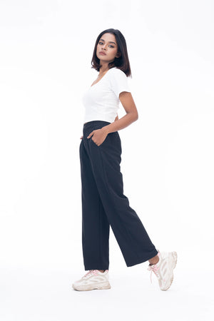 Woman wearing a white top and black pants on a white background