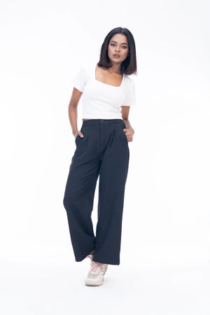 Woman wearing a white top and dark blue wide-leg pants on a white background