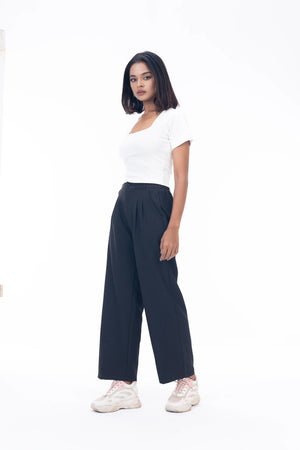 Woman wearing a white top and navy pants on a white background