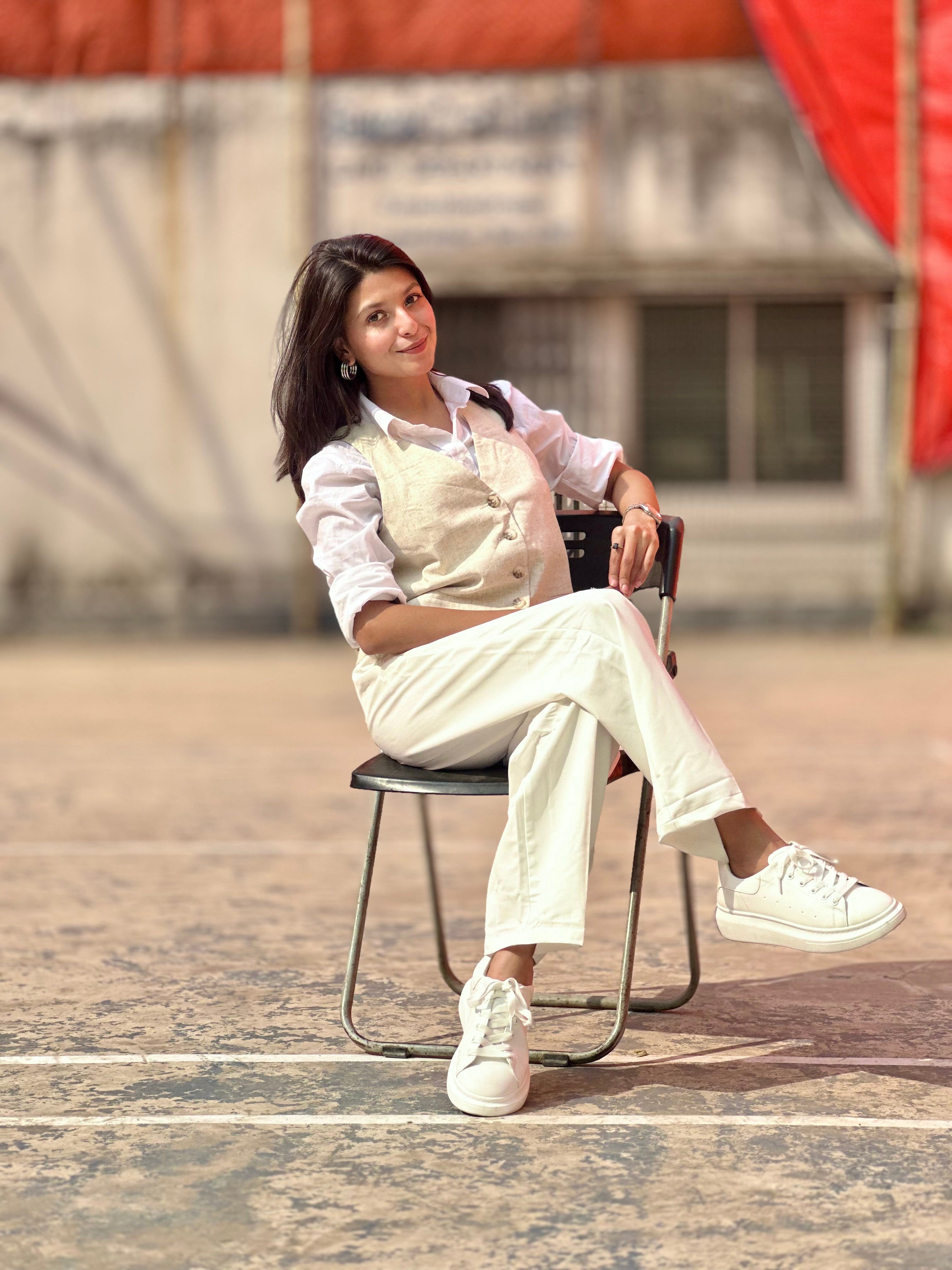 Woman sitting on a chair wearing a white outfit with a red and gray blurred background