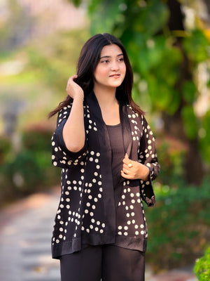 Woman wearing a black polka dot jacket outdoors with greenery in the background
